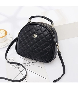 Detailed view of black quilted round bag with gold clover logo and top handle
