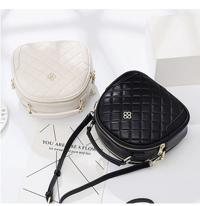Detail of quilted leather mini bags with clover logo and gold-tone zippers on a white background