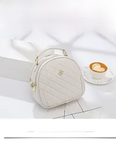 Detailed close-up of quilted rhombic texture and gold clover logo on ivory mini bag