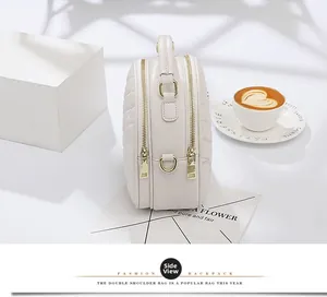 Side view of cream quilted leather crossbody bag with double gold zipper compartments