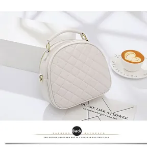 Detail view of the quilted beige crossbody bag back side with gold hardware and top handle