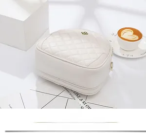 Detail of white quilted handbag with golden metal logo and elegant rhombus texture