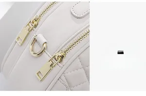 Detailed macro view of quilted cream leather texture and polished gold dual zipper pulls