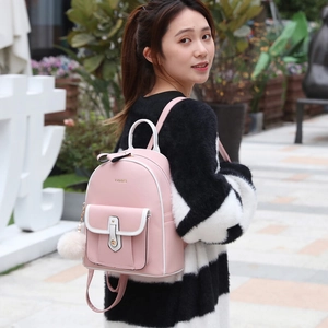 Sac à dos mode en cuir rose avec liseré blanc et breloque peluche portée par un modèle