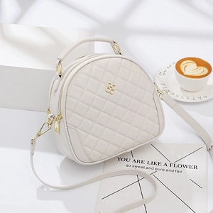 Quilted cream crossbody bag with gold floral logo and dual zipper on white background