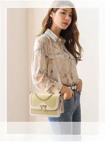 Détail d'un sac bandoulière en cuir jaune avec chaîne dorée et fermoir en métal doré