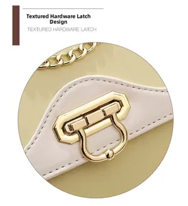 Gros plan du fermoir métallique doré et de la chaîne sur un sac bandoulière beige