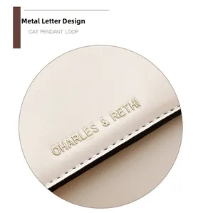 Dettaglio del logo in metallo dorato sulla superficie della borsa a tracolla in pelle bianca