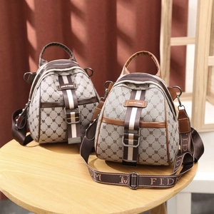 Chic monogram backpack with leather trim and striped strap shown on a wooden table
