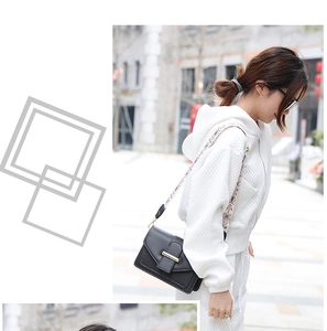 Detail of black leather crossbody square bag featuring a stylish wide patterned strap