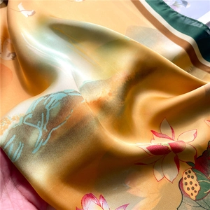 Detailed close-up of glossy silk scarf texture with red lotus and mountain print