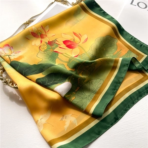 Macro detail of silk scarf featuring lotus and crane patterns on a golden vintage tray