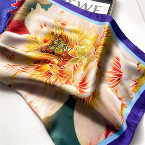 Detailed macro view of colorful lotus print on a silky lightweight scarf with hemmed edges