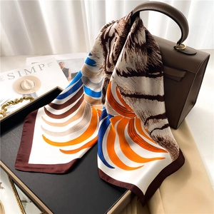 Elegant silk scarf with animal tiger print draped over a brown designer handbag
