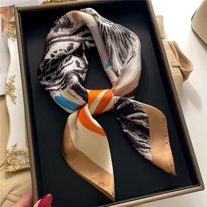 Close-up of silk scarf with tiger print and color blocking in a grey gift box