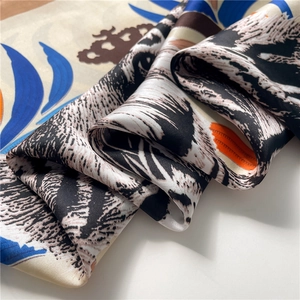 Macro detail of silk scarf showing tiger print and crown pattern with satin texture