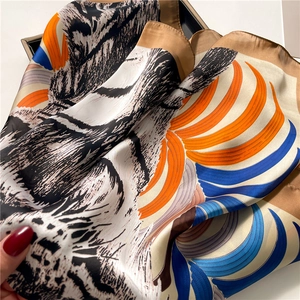 Detail shot of a silk scarf featuring black-and-white tiger print and orange-blue feathers