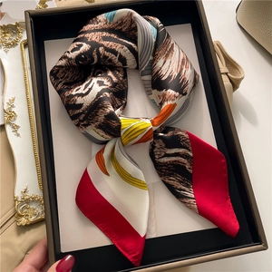 Macro detail of silk scarf with tiger print and red color block in elegant gift box