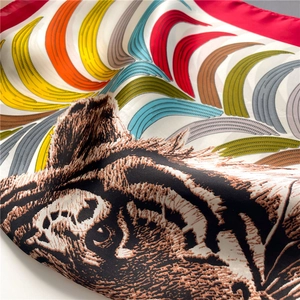 Macro shot of tiger print silk scarf showing smooth texture and red hand-rolled edges