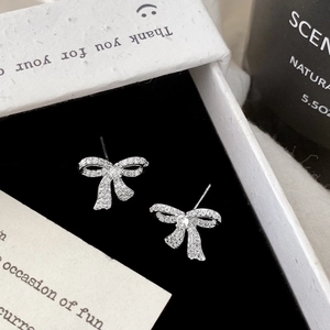 Macro shot of silver bow stud earrings with sparkling cubic zirconia in a jewelry box
