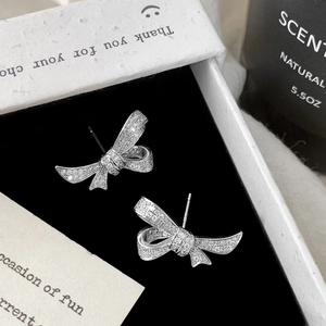 Macro shot of sparkling bow stud earrings with micro-paved zircons on black velvet