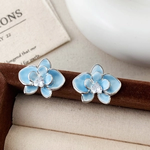Elegante hellblaue Emaille Blumenohrstecker mit Herz Zirkon auf dunklem Samthintergrund