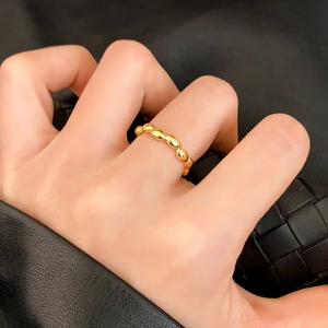 Elegant gold croissant ring with beaded design worn on hand against a black leather background
