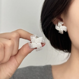 Fashionable silver windmill earrings in a woven texture on model for a premium look