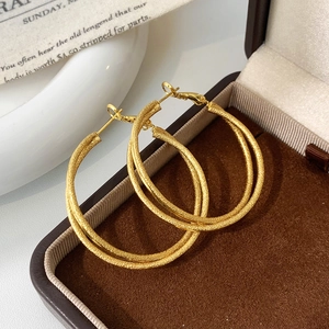 Close-up of gold oversized geometric hoop earrings with textured glitter finish