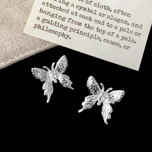 Detail silberner Schmetterlingsstecker mit gehämmerter Textur und Marquise-Kristall