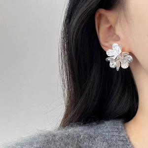 Elegant silver flower stud earrings with hammered metal texture shown on a model