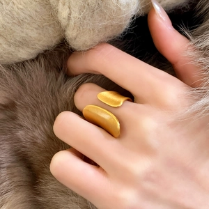 Elegant gold leaf brushed ring worn by a model against a warm luxury fur background