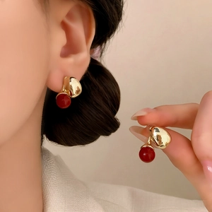 Elegant gold drop earrings with deep red pearls for a minimalist and vintage look