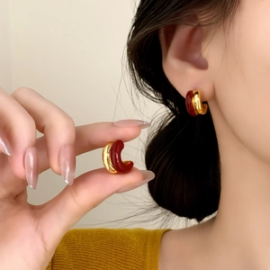 Retro C-shaped gold hoops with red enamel finish shown on a model for autumn style
