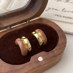 Close-up of golden enamel hoop earrings in a luxury velvet wooden jewelry box