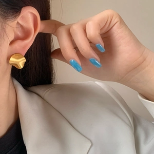 Minimalist gold irregular wave stud earrings with matte brushed finish on model