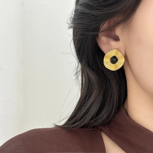 Vintage gold spiral earrings with square black gemstone on model ear for elegant style