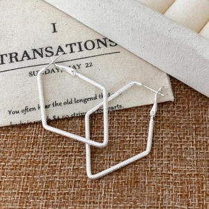 Macro detail of silver geometric earrings with a unique frosted sandblasted texture