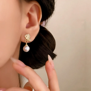 Boucles d'oreilles papillon élégantes avec opale et perle portées par un modèle