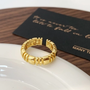 Detailed close-up of a gold adjustable open ring featuring a segmented geometric design