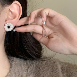 Detail of floral daisy stud earring with white pearls and a black center stone