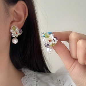 Detailed close-up of handmade floral bead earrings featuring a large drop pearl charm