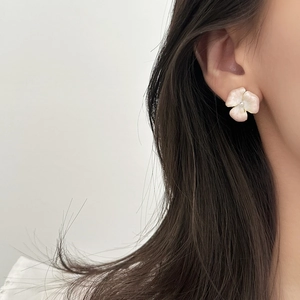 Elegante orecchino a fiore in smalto rosa con perla indossato da una modella