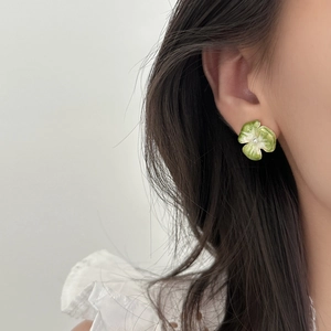 Dettaglio dell'orecchino a fiore in smalto verde con perla sulla modella
