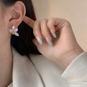 Eleganti orecchini a fiore con petali di perla rosa e bordo dorato sulla modella
