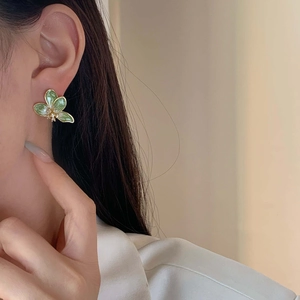 Eleganti orecchini a fiore verdi placcati in oro con cristalli lucenti sul modello