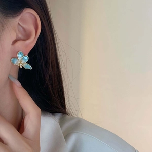 Eleganti orecchini a fiore in smalto blu francese con cristalli sulla modella