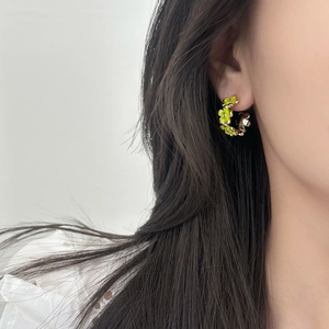 Orecchini a cerchio floreali dorati con fiori in smalto giallo-verde su modella