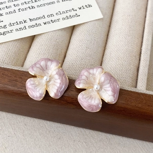 Dettaglio di orecchini a fiore in smalto viola con perla su portagioie in stile vintage