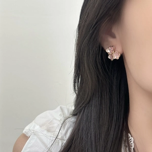Elegant floral drop oil earrings with pink layered petals and gold trim on female model